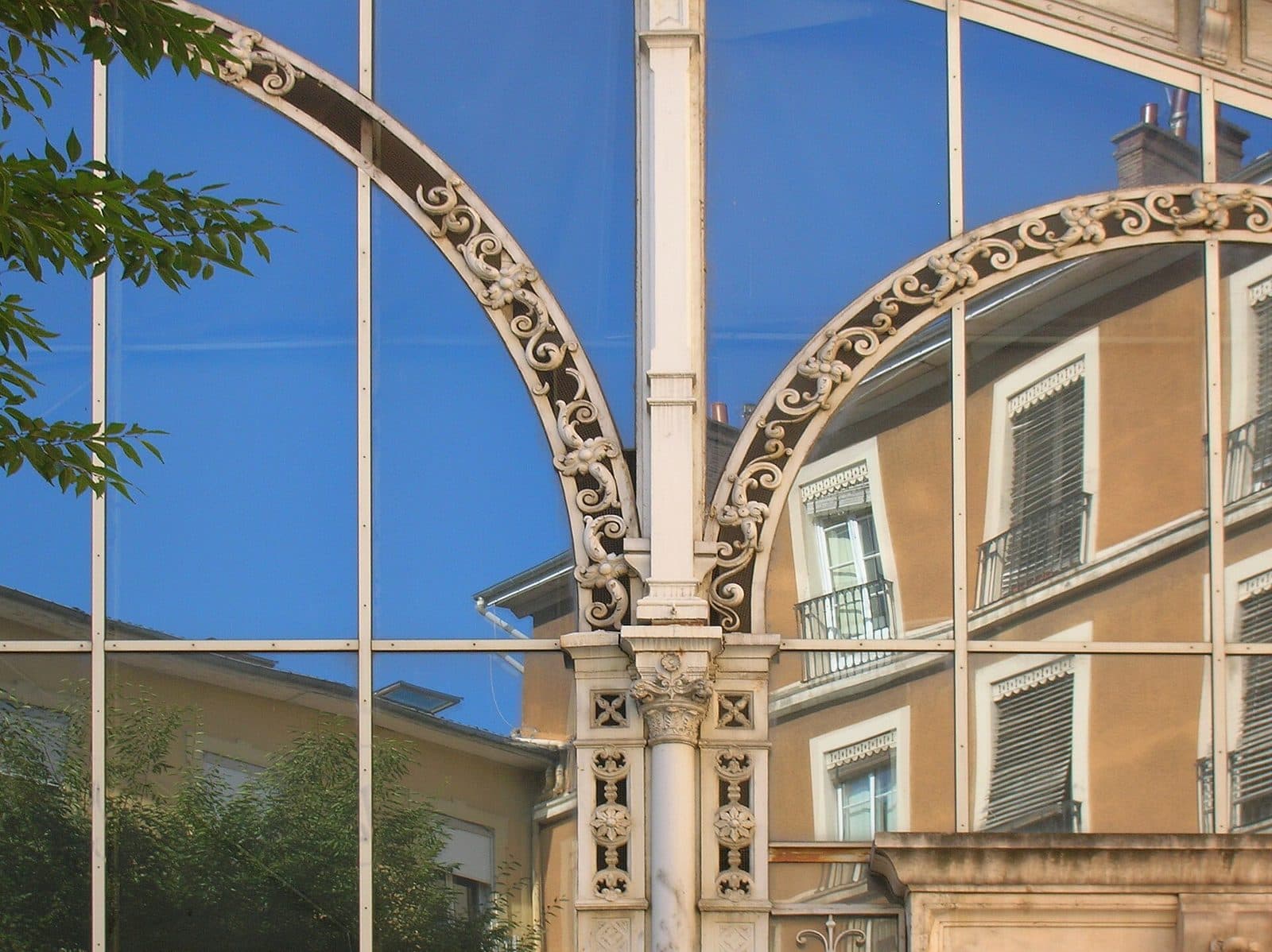 Un arc de fonte de la halle Sainte-Claire encadrant les façades voisines de la place.
