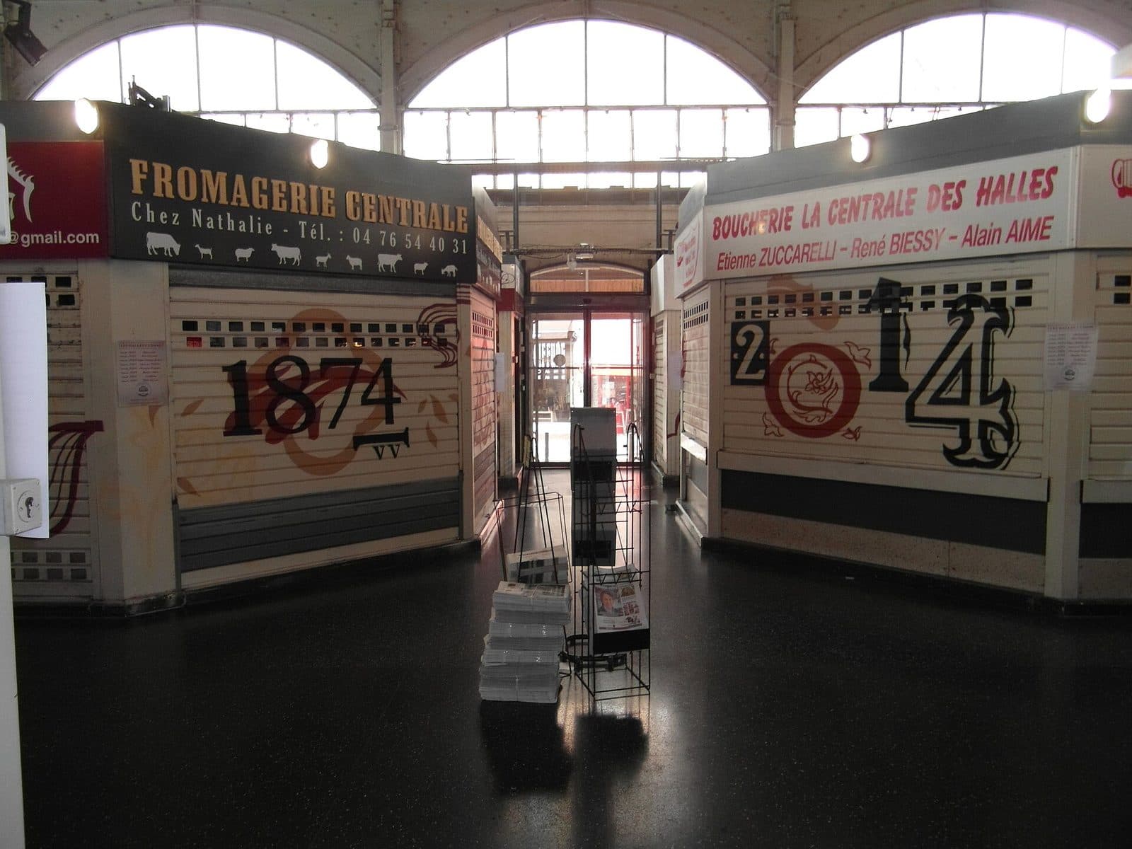Les arcades intérieures de la halle et les enseignes des commerçants au-dessus des étals.