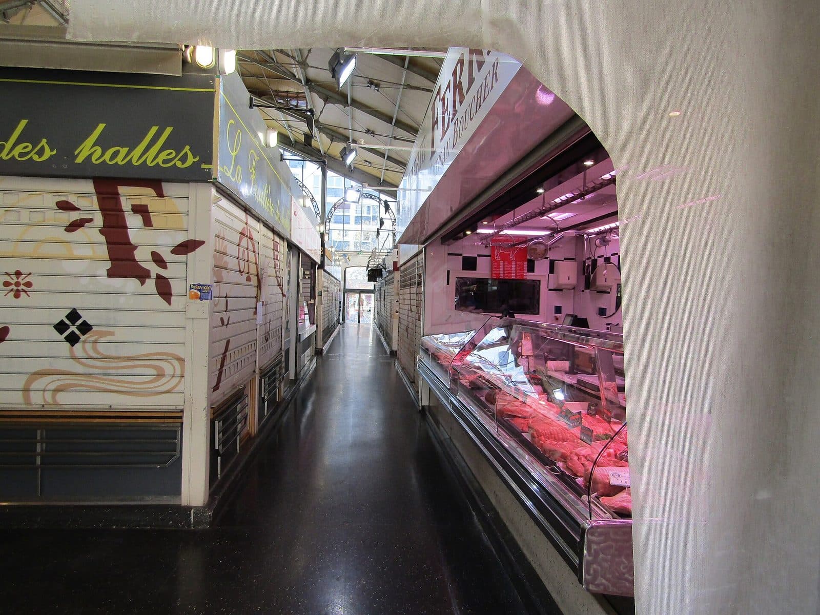 Un étal de la halle Sainte-Claire, sa vitrine réfrigérée éclairée dans la pénombre de l'allée.