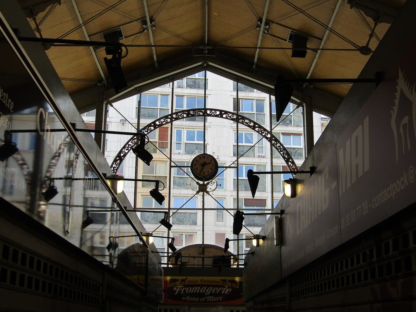 L'intérieur de la halle vu depuis l'allée centrale : la charpente, l'horloge et la grande verrière du pignon.