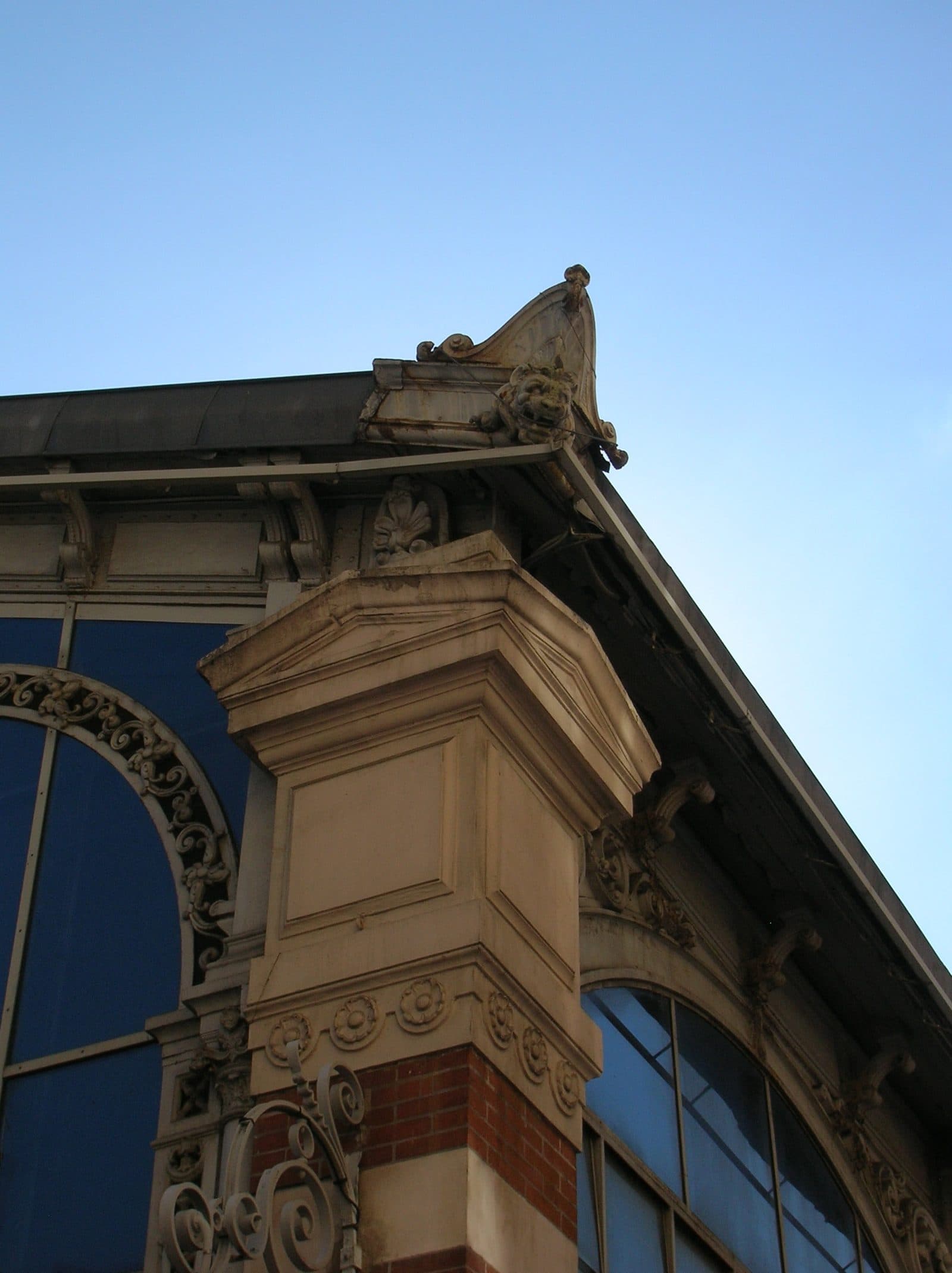 Acrotère d'angle en forme de tête de lion, sculpté à la corniche de la halle Sainte-Claire.