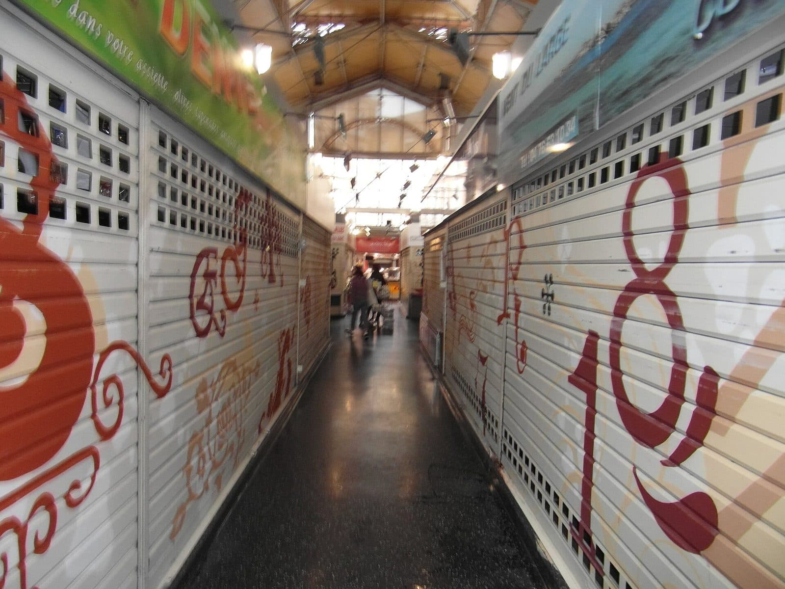 L'allée centrale de la halle Sainte-Claire, bordée des rideaux peints des étals.