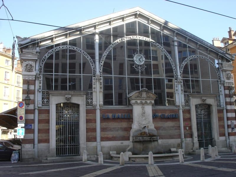 Le pignon de la halle Sainte-Claire, son horloge et la fontaine de pierre adossée à la façade.